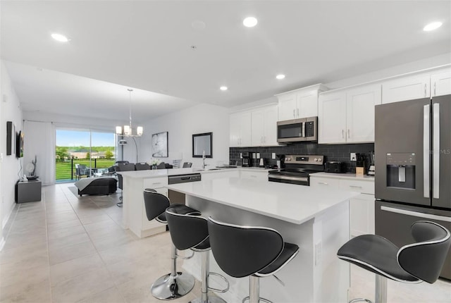 kitchen with pendant lighting, a breakfast bar, white cabinetry, stainless steel appliances, and kitchen peninsula