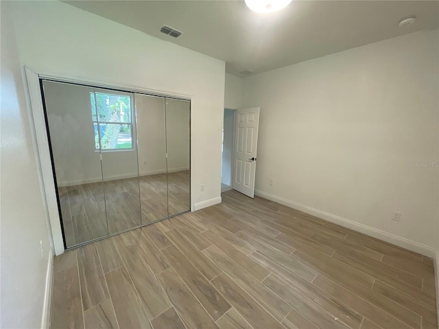 unfurnished bedroom with light wood-type flooring and a closet