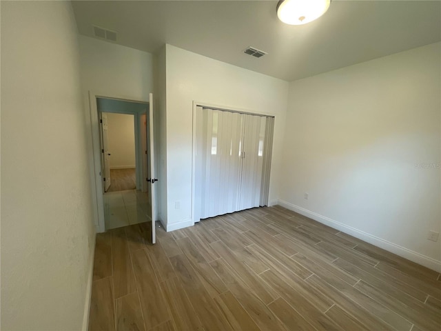 unfurnished bedroom with light hardwood / wood-style flooring and a closet