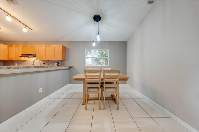 tiled dining space with a textured ceiling and rail lighting