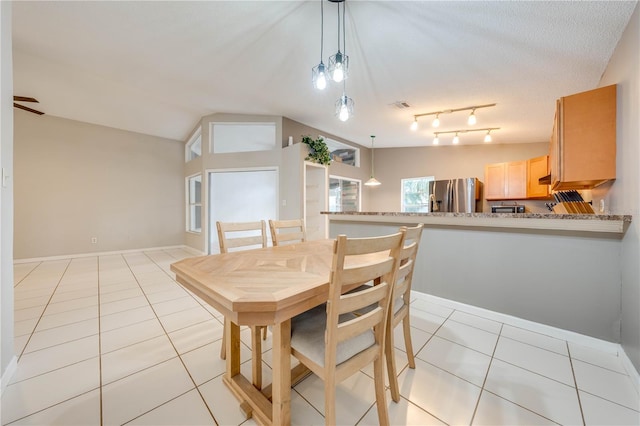 dining space featuring light tile patterned floors, a textured ceiling, and lofted ceiling