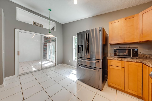 kitchen featuring light tile patterned floors, stainless steel appliances, decorative light fixtures, and light brown cabinetry