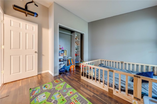 bedroom with dark hardwood / wood-style flooring, a crib, and a closet