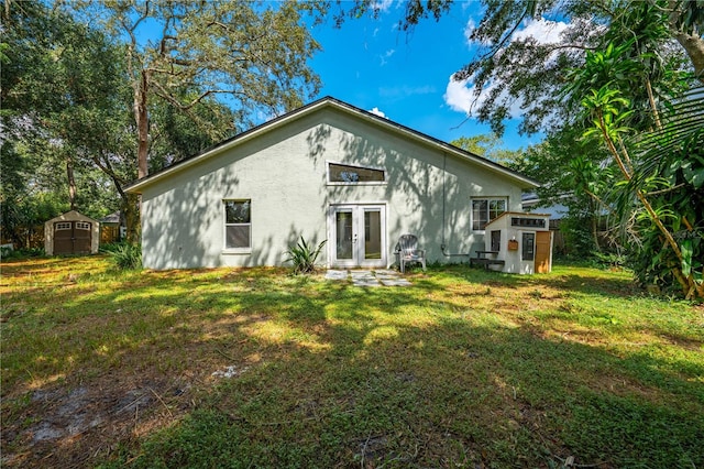 rear view of property with a lawn, a storage shed, and french doors