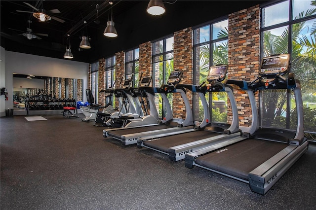 exercise room featuring ceiling fan and a high ceiling