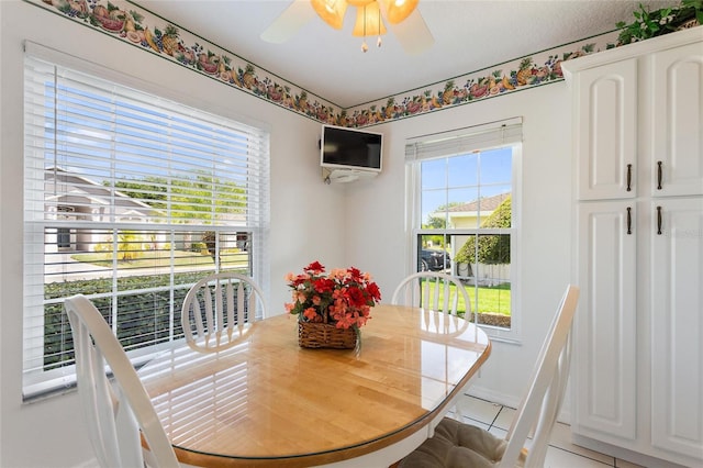 tiled dining space with plenty of natural light and ceiling fan