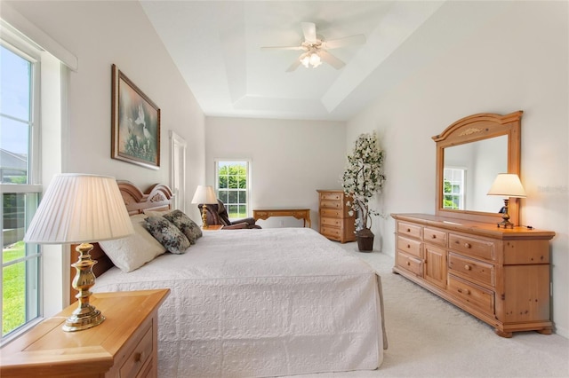 carpeted bedroom with a raised ceiling and ceiling fan