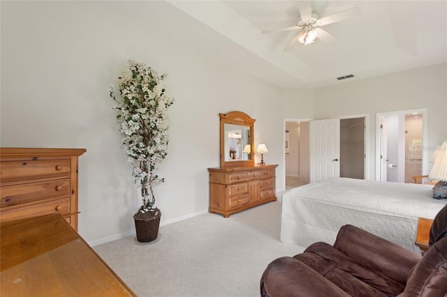 bedroom with light carpet, a towering ceiling, a walk in closet, ceiling fan, and a closet