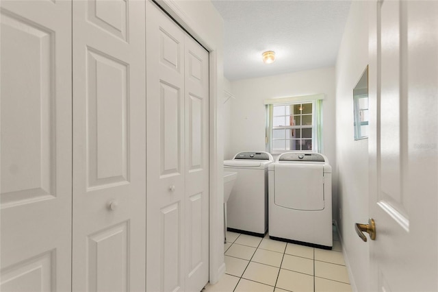 clothes washing area featuring washer and dryer, light tile patterned floors, and a textured ceiling