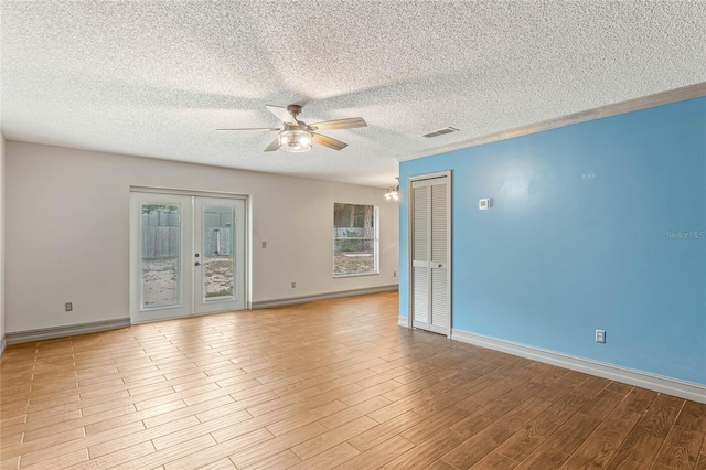 unfurnished room featuring french doors, ceiling fan with notable chandelier, a textured ceiling, and light hardwood / wood-style flooring