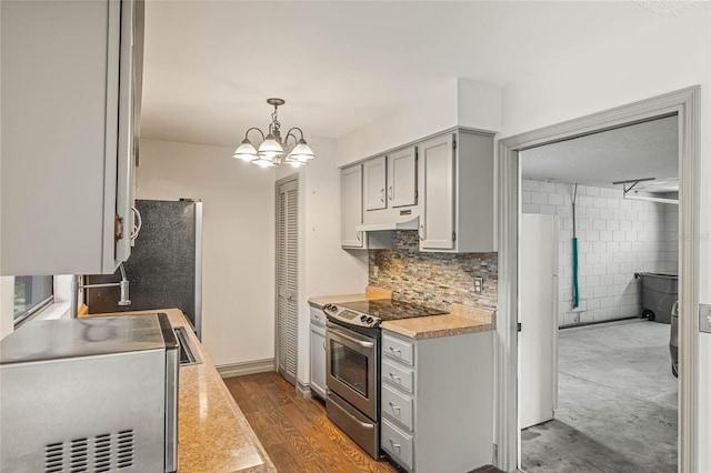 kitchen featuring an inviting chandelier, dark hardwood / wood-style floors, decorative light fixtures, tile walls, and appliances with stainless steel finishes