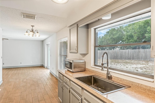 kitchen with hanging light fixtures, light wood-type flooring, a wealth of natural light, and sink