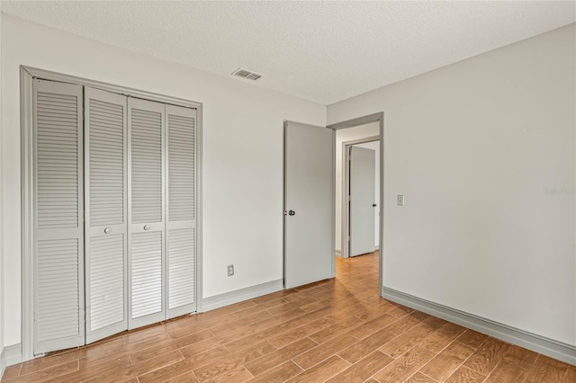 unfurnished bedroom featuring a textured ceiling, light hardwood / wood-style floors, and a closet