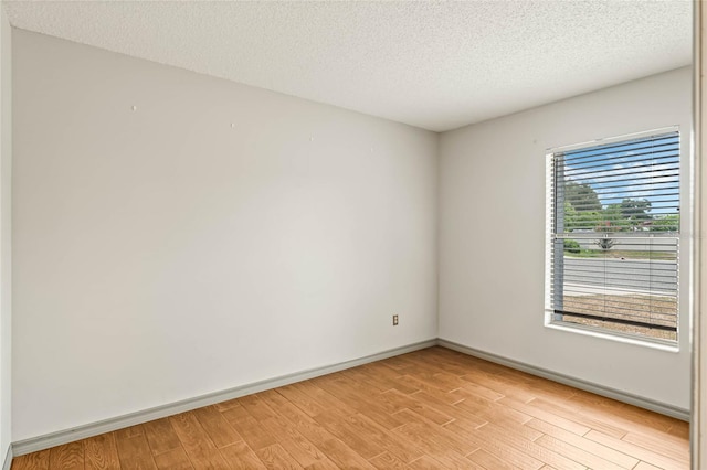 unfurnished room with light hardwood / wood-style floors and a textured ceiling