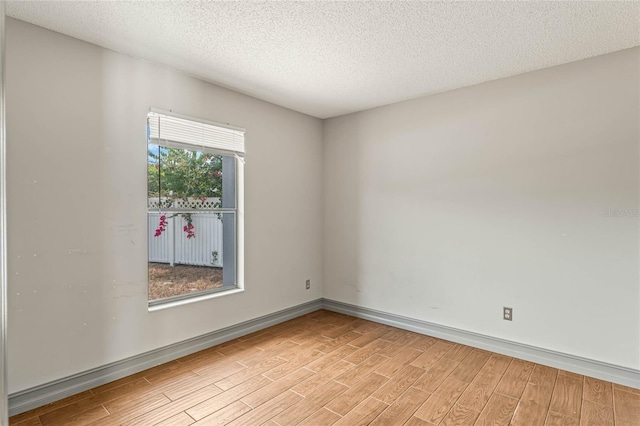 empty room featuring a textured ceiling and light hardwood / wood-style flooring