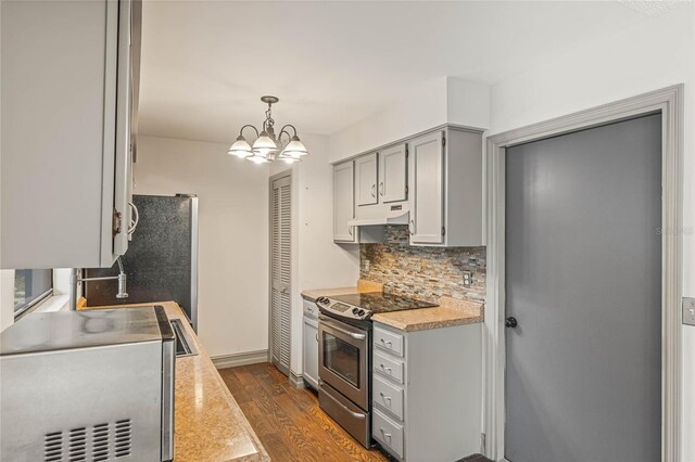 kitchen with gray cabinetry, hanging light fixtures, stainless steel appliances, an inviting chandelier, and dark hardwood / wood-style flooring