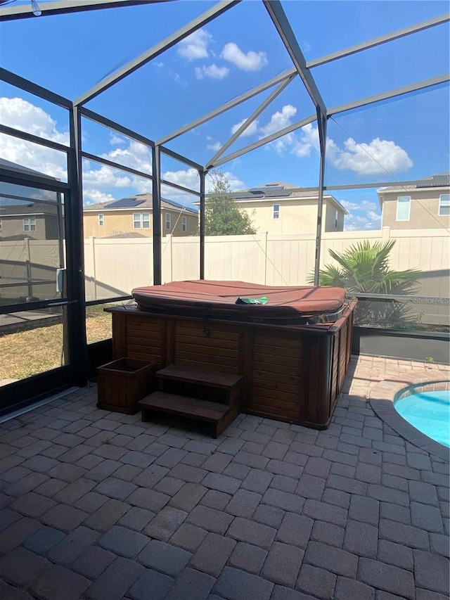 view of patio with glass enclosure and a swimming pool with hot tub