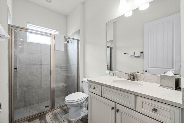 bathroom with vanity, toilet, and a shower with door