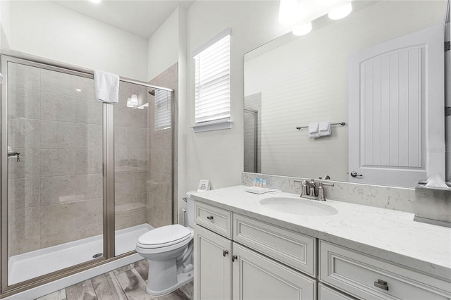 bathroom with toilet, a shower with door, vanity, and hardwood / wood-style flooring