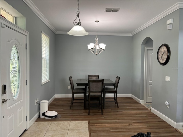 tiled dining room with an inviting chandelier and ornamental molding