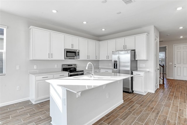 kitchen featuring white cabinetry, a center island with sink, stainless steel appliances, and sink