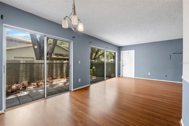 empty room featuring a textured ceiling, hardwood / wood-style flooring, and a notable chandelier