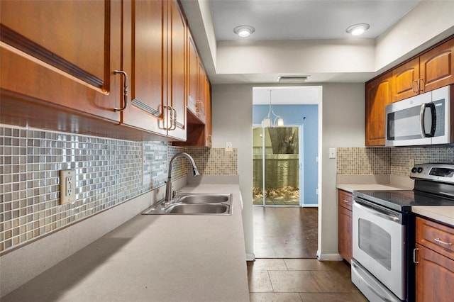 kitchen with pendant lighting, backsplash, sink, and appliances with stainless steel finishes