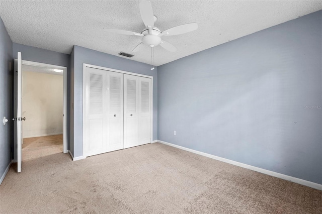 unfurnished bedroom with light carpet, a textured ceiling, a closet, and ceiling fan