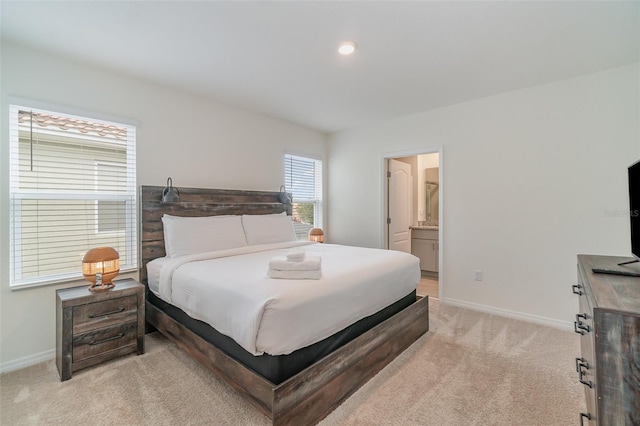 bedroom featuring light colored carpet and ensuite bath