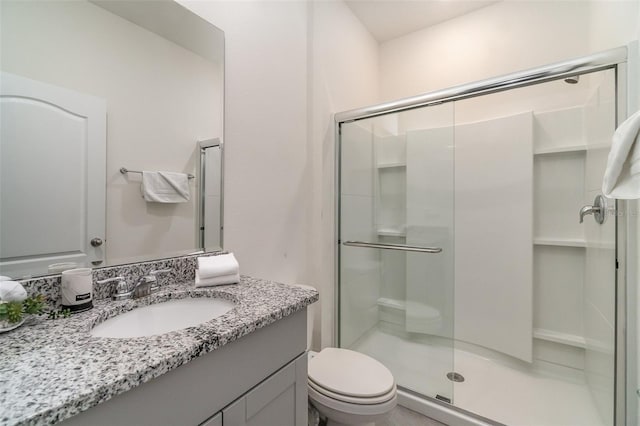 bathroom with vanity, toilet, and a shower with door