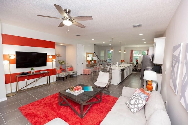 tiled living room with ceiling fan, sink, and a textured ceiling