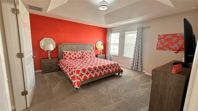 bedroom featuring a textured ceiling, dark carpet, and a tray ceiling