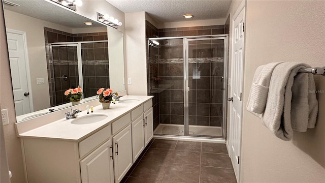 bathroom featuring walk in shower, vanity, tile patterned flooring, and a textured ceiling