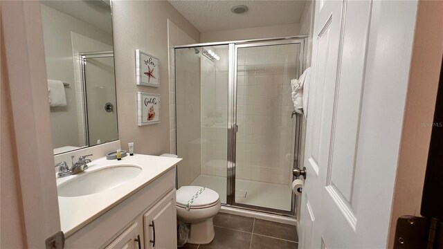 bathroom featuring vanity, a textured ceiling, tile patterned floors, toilet, and walk in shower