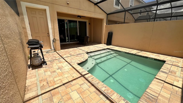 view of swimming pool featuring ceiling fan, a patio area, and glass enclosure