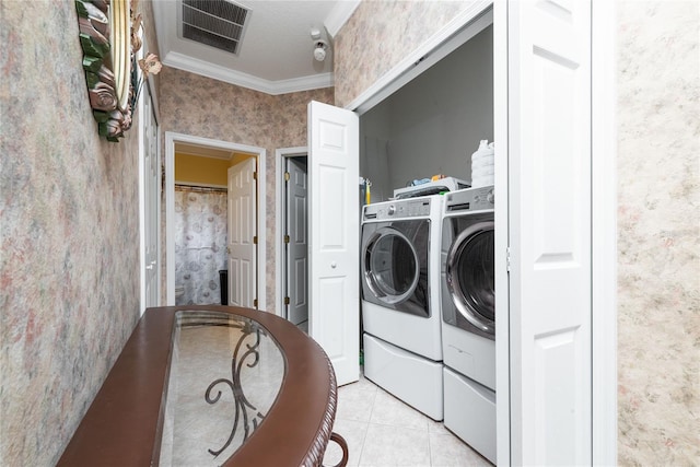 laundry room featuring crown molding, light tile patterned floors, and washer and dryer