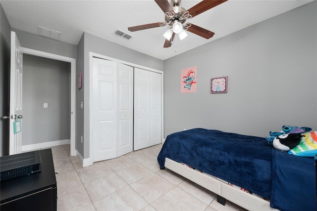 bedroom featuring ceiling fan, a textured ceiling, a closet, and light tile patterned flooring