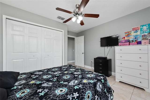 tiled bedroom featuring a textured ceiling, ceiling fan, and a closet