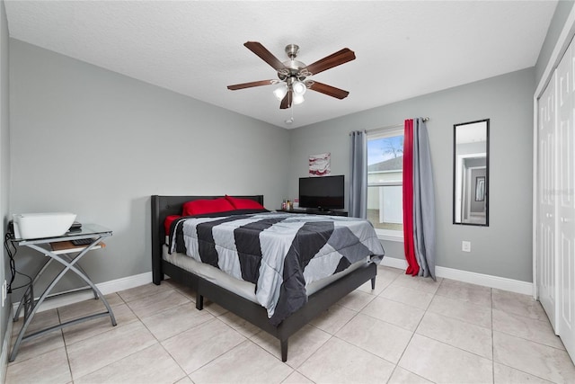 tiled bedroom with ceiling fan, a closet, and a textured ceiling