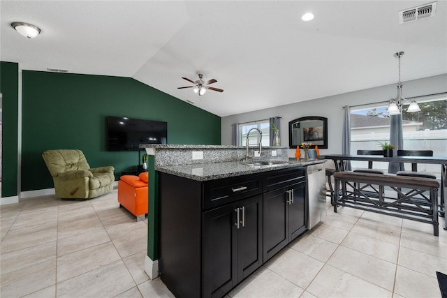 kitchen featuring lofted ceiling, dishwasher, pendant lighting, light stone counters, and sink