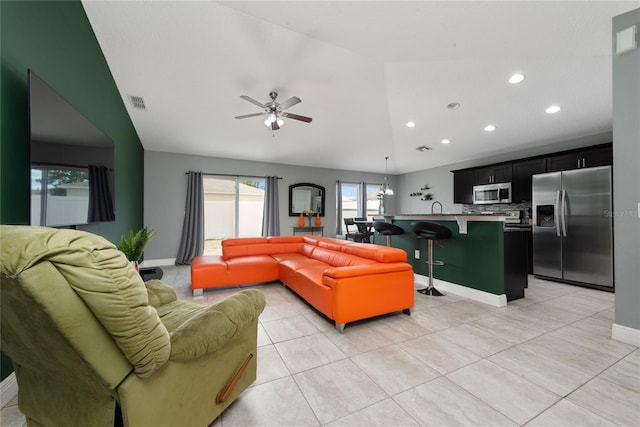 tiled living room with vaulted ceiling, ceiling fan, and sink