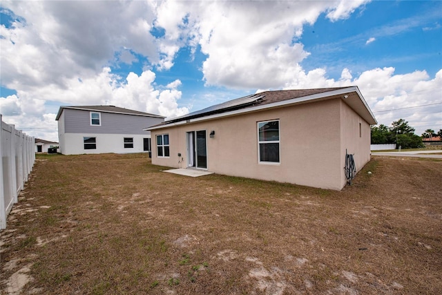 rear view of property with solar panels and a yard