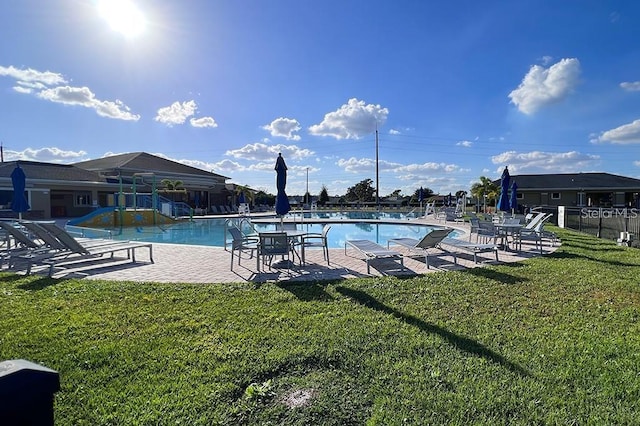 view of swimming pool featuring a patio area, a yard, and a playground