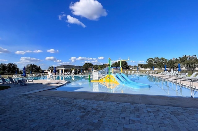 view of swimming pool with a playground and a patio area