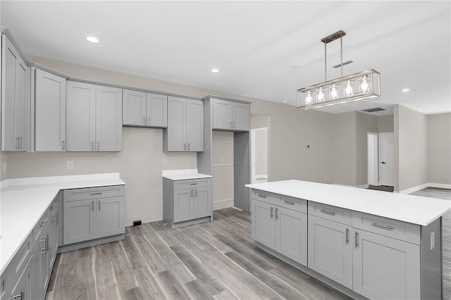 kitchen featuring light wood-type flooring, pendant lighting, light countertops, and gray cabinetry