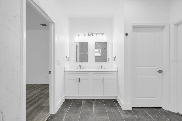 full bath with double vanity, a sink, visible vents, and baseboards