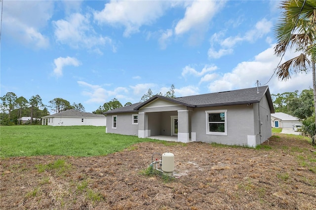 back of property featuring a patio area, a yard, and stucco siding