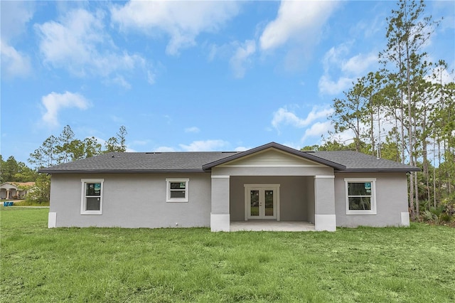 rear view of property with a shingled roof, a yard, french doors, a patio area, and stucco siding