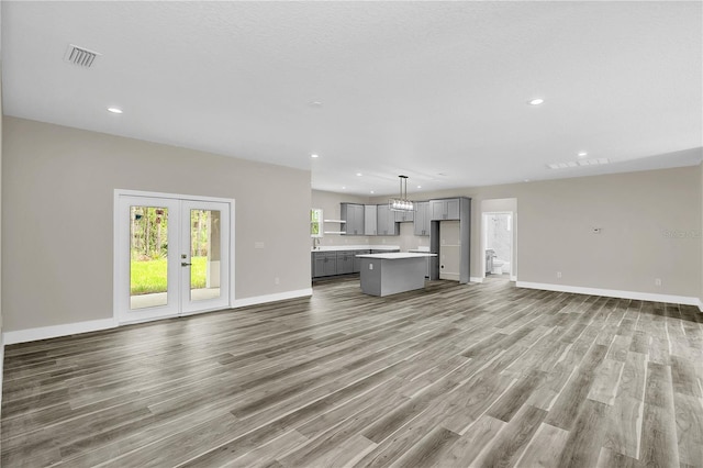 unfurnished living room with recessed lighting, wood finished floors, visible vents, baseboards, and french doors