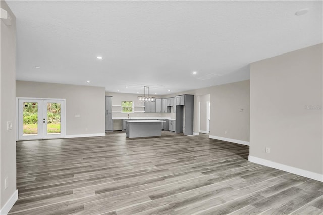 unfurnished living room with plenty of natural light, baseboards, wood finished floors, and recessed lighting